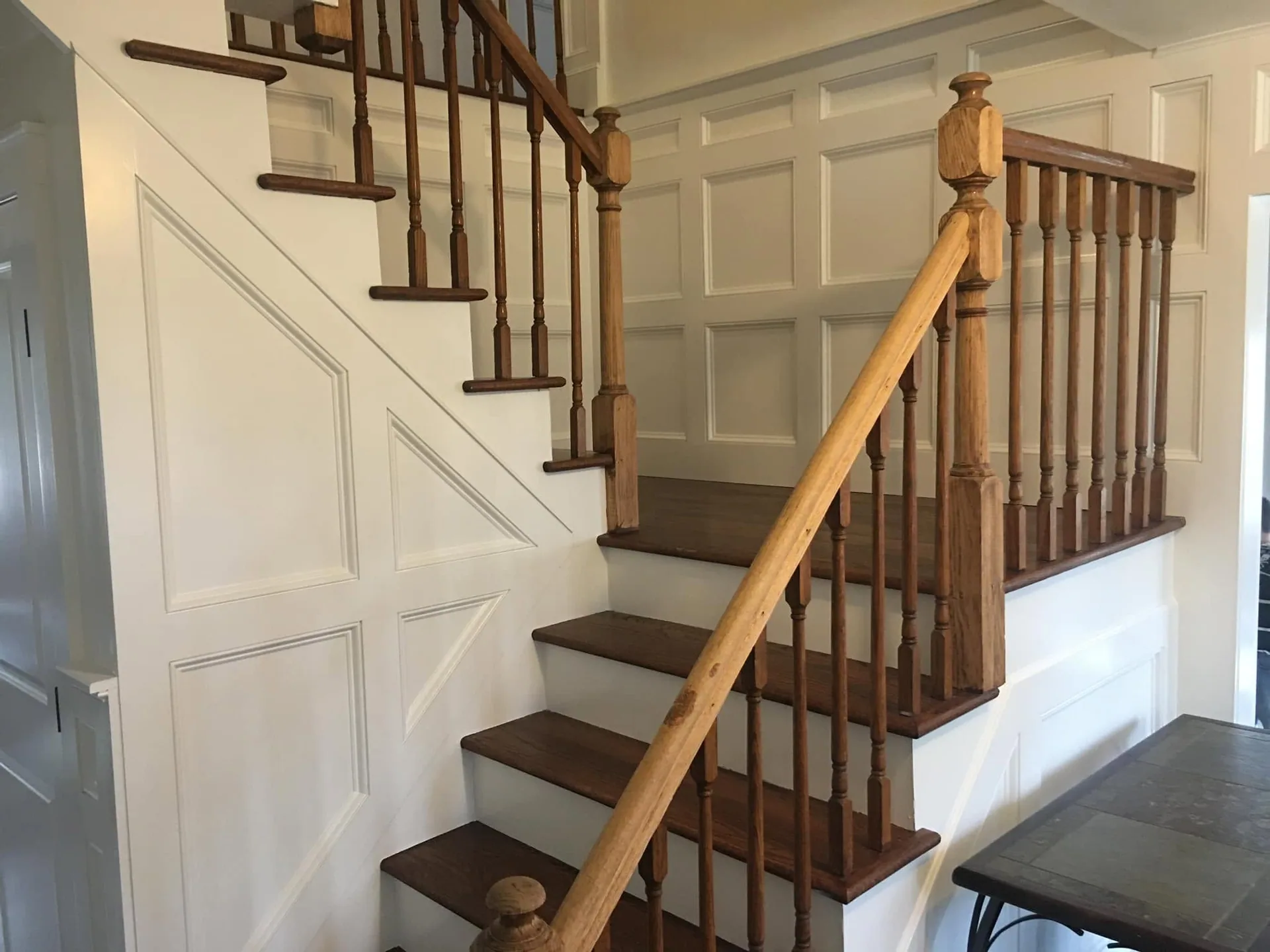 Oak staircase remodel with custom wainscoting paneling by North South Construction